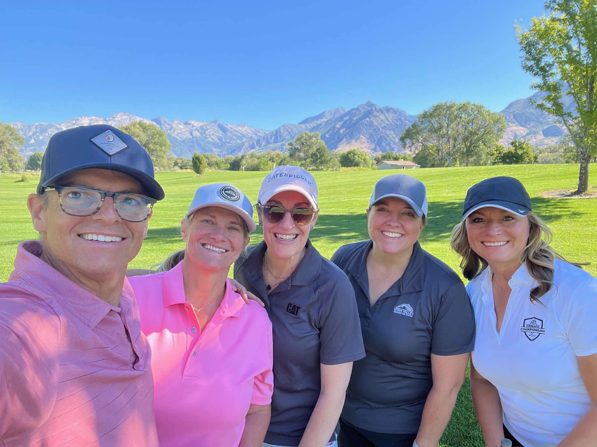 Smiling Utah Valley Chamber members on a golf course with mountains in the background.