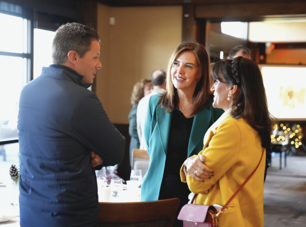 Three professionals networking at a Utah Valley Chamber of Commerce event.